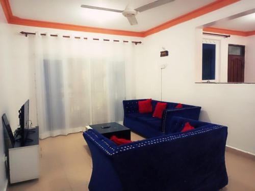 a living room with two blue chairs and a tv at Lovely and spacious apartment with swimming pool in Mtwapa