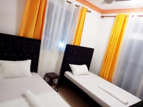 two beds in a room with yellow curtains at Lovely and spacious apartment with swimming pool in Mtwapa
