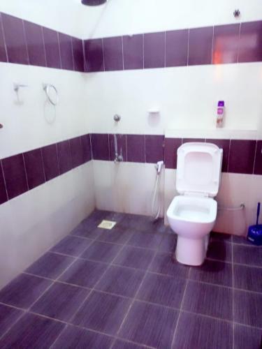 a bathroom with a toilet and a purple tiled floor at Lovely and spacious apartment with swimming pool in Mtwapa
