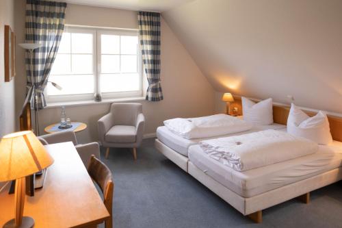una habitación de hotel con 2 camas y una silla en Gästehaus Kölfhamm 2, en Sankt Peter-Ording