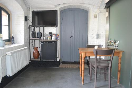 a dining room with a table and a blue door at Bed & Breakfast Fort Bakkerskil in Nieuwendijk