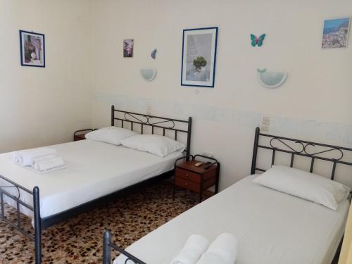 two twin beds in a room with white walls at KOTSIFAS ROOMS in Tyros