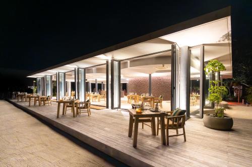 a restaurant with tables and chairs on a deck at night at Madifushi Private Island in Meemu Atoll