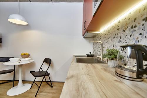 a kitchen with a sink and a table with chairs at City Rooms Arcadia Self Check-In in Odesa