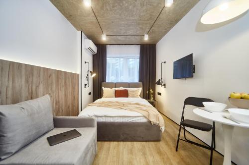 a bedroom with a bed and a couch and a table at City Rooms Arcadia Self Check-In in Odesa