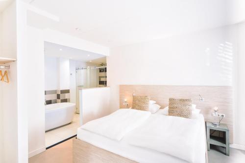 a white bedroom with a bed and a bath tub at Logement Overzee in Nes