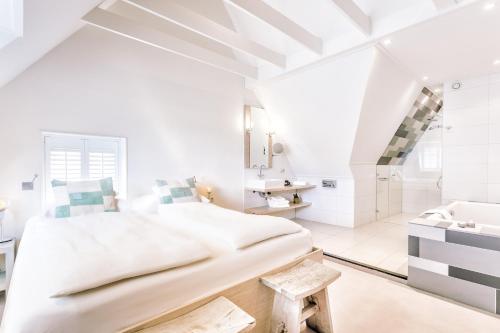 a white bedroom with a large bed and a sink at Logement Overzee in Nes