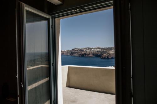 a room with a view of the ocean from a window at Akrorama private villas and suites in Akrotiri