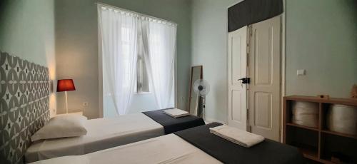 a bedroom with two beds and a window and a door at Hostel A Casa da Árvore in Faro