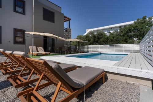 een zwembad met 2 ligstoelen en een parasol bij Villa Astravi in Ialyssos