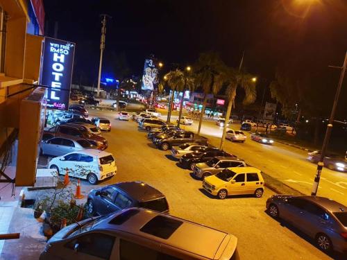 um monte de carros estacionados num parque de estacionamento à noite em Family Budget em Kampong Telok Sisek