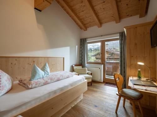 a bedroom with a bed and a desk and a window at Schnapperhof in Going am Wilden Kaiser