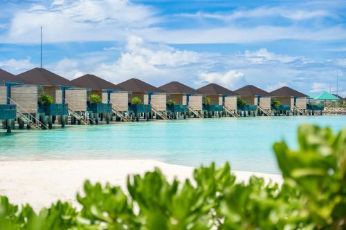 a view of a beach with a row of huts at Madifushi Private Island in Meemu Atoll