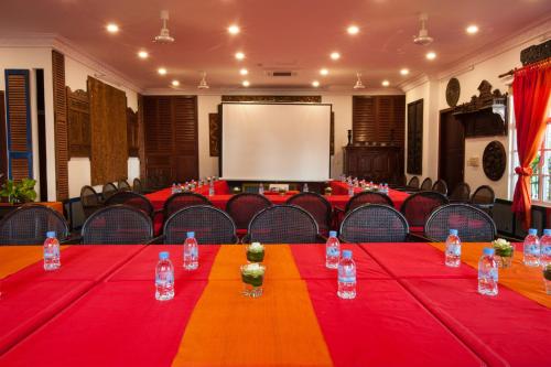 a conference room with red tables and chairs and a white screen at Khmer Surin Boutique Guesthouse in Phnom Penh