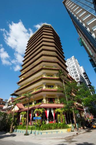 a tall building with trees in front of it at Khmer Surin Boutique Guesthouse in Phnom Penh