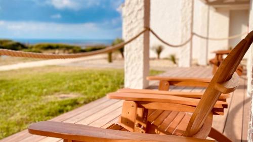 a wooden bench on a porch with a view of the ocean at Hôtel Île de Lumière in La Cotinière