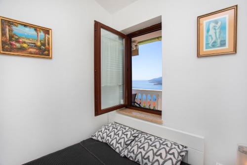 a room with a window with a pillow and a view at Greenhouse family apartments in Rabac