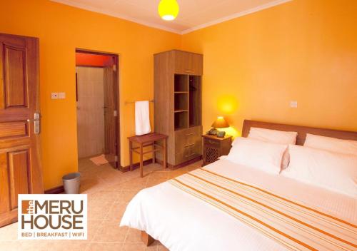 a bedroom with a bed and a yellow wall at The Meru House in Nkubu