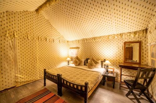 a bedroom with a bed and a desk and a mirror at Tiger Machan in Sawāi Mādhopur