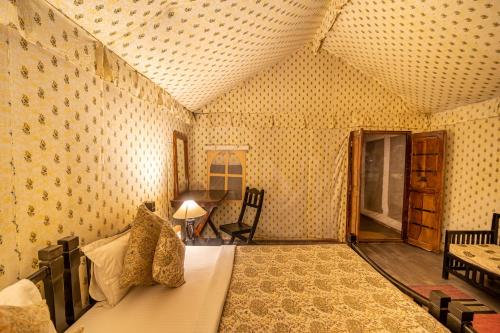 a bedroom with a bed and a desk in a room at Tiger Machan in Sawāi Mādhopur