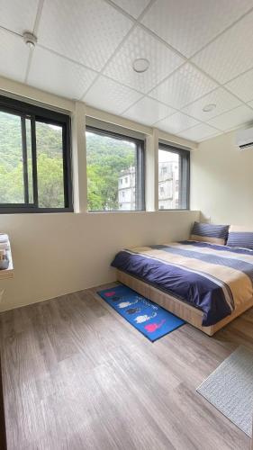 Un dormitorio con una cama grande en una habitación con ventanas. en 漫旅溫泉會館-愛娜, en Jiaoxi