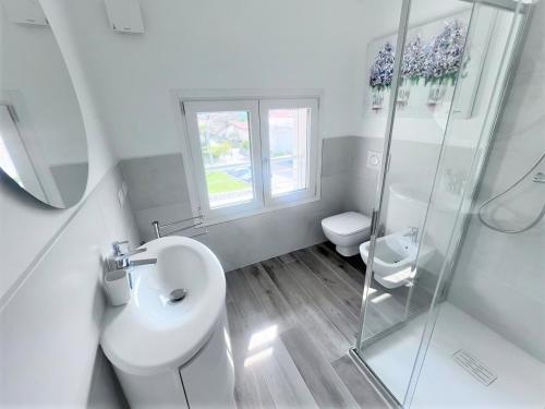 a white bathroom with a toilet and a shower at VILLA CLAUDIA WITH PRIVATE POOL in Colico