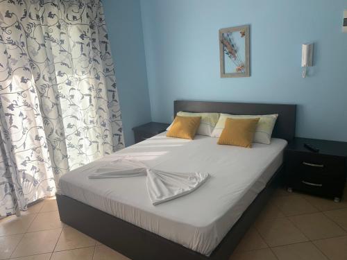 1 dormitorio con 1 cama con sábanas blancas y almohadas amarillas en Julia Apartments en Vlorë