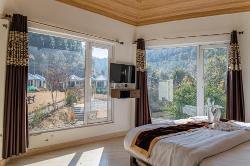 a bedroom with a large window with a bed and a tv at Blossom Bliss Resort in Bhīm Tāl