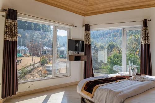 - une chambre avec une grande fenêtre, un lit et une télévision dans l'établissement Blossom Bliss Resort, à Bhimtal