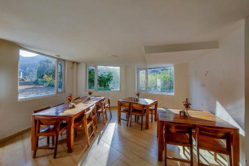 a large dining room with wooden tables and windows at Blossom Bliss Resort in Bhīm Tāl