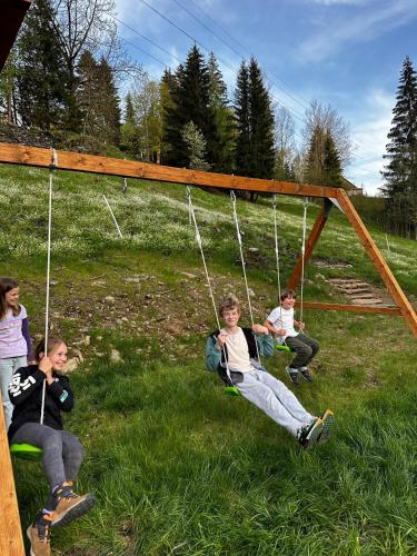 a group of people sitting on a swing at Rákosárna Suites & Apartments in Špindlerův Mlýn