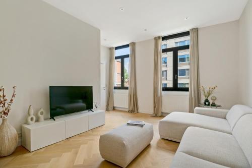 ein weißes Wohnzimmer mit einem TV und einem Sofa in der Unterkunft Zuid's Charming Gem Apt in Antwerpen