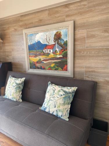 a couch with two pillows sitting under a painting at 3ColoursBlue Guest House in Mossel Bay
