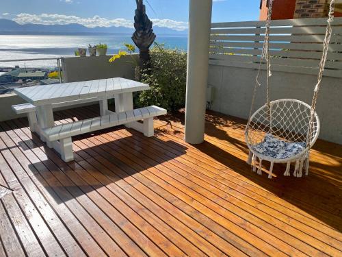 a porch with a bench and a swing and a chair at 3ColoursBlue Guest House in Mossel Bay