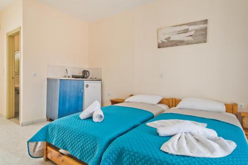 twee bedden in een kamer met blauwe lakens en handdoeken bij Venetia Studios in Karpathos