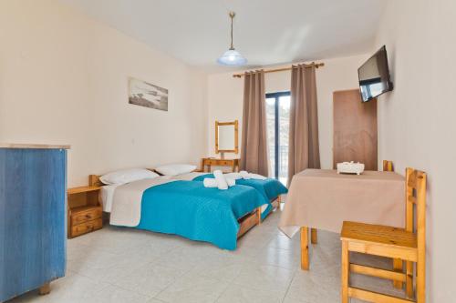 een slaapkamer met een bed en een tafel en een televisie bij Venetia Studios in Karpathos