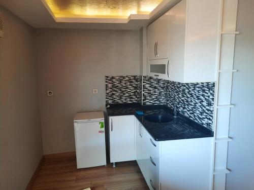 a small kitchen with white cabinets and a black counter top at Kuşadası Apart Dairelerimiz in Kuşadası