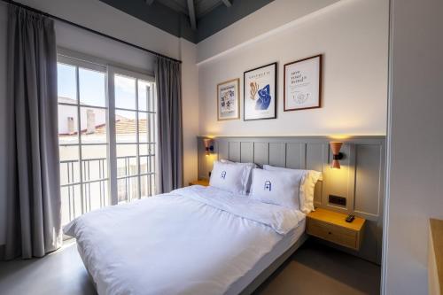 a bedroom with a large white bed and a window at Blue Alle Alaçatı in Alaçatı