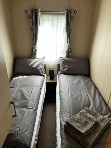 two beds in a small room with a window at Whitstable, CW18, 2 bed park home, Alberta Holiday Park in Seasalter