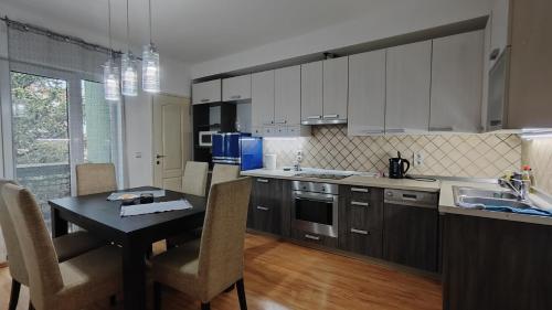 a kitchen with a table and chairs and a kitchen with white cabinets at Quiet place apartman Markovic in Požarevac