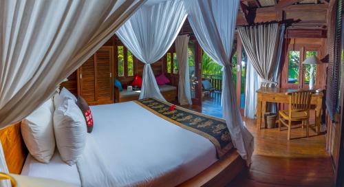 een slaapkamer met een bed met gordijnen en een bureau bij Villa Neyang in Ubud