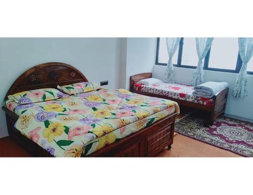a bedroom with a bed with a floral comforter at Basudhalaya Home Stay, Darjeeling in Darjeeling