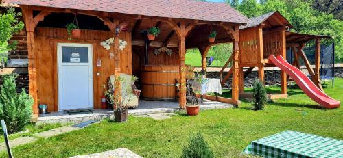 a wooden gazebo with a slide and a playground at Casa Pintea de Sub Coastă in Breb