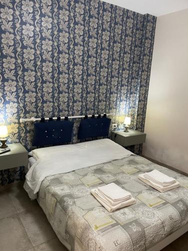 1 dormitorio con 1 cama con 2 mesas y toallas en Recente costruzione, centrale, tutti i comfort, en Pozzallo