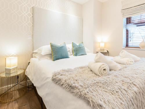 1 dormitorio blanco con 1 cama blanca grande con almohadas azules en Bwthyn Bach, en Dyffryn