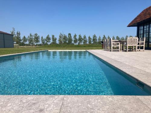 a swimming pool with two chairs and a table at Kapelhoeve in De Haan