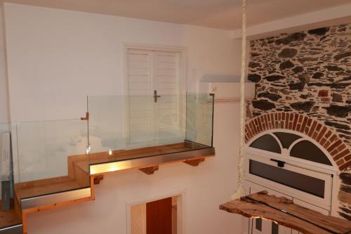 a glass staircase in a room with a stone wall at Cane’s Family Guest House in Plomarion