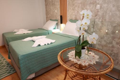 2 Betten in einem Zimmer mit einem Tisch und Blumen in der Unterkunft Cane’s Family Guest House in Plomari