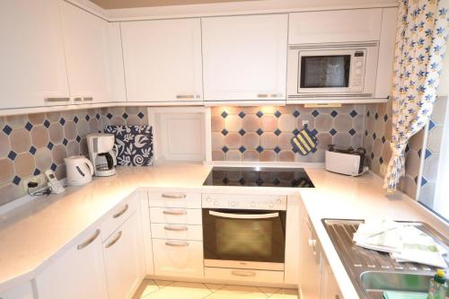 uma cozinha com armários brancos e um forno com placa de fogão em Haus-Neumann em Westerland