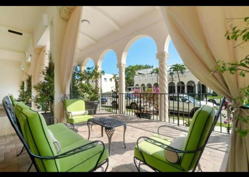 un patio con sillas verdes y una mesa en el balcón en Tropical Palm Beach 2 Bedroom 2 Bathroom Suite POOL -BEACH 2 Blocks Valet Parking Included, en Palm Beach